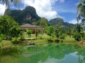 a house with a pond in front of a mountain at Baan Blue River 2 bedrooms in Ban Nai Sa