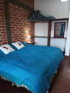 a large blue bed in a room with a brick wall at Cabañas Boutique NanakaUta in El Ceibal