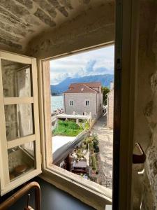 a window with a view of a building and the ocean at Bel Composto Apartments in Perast
