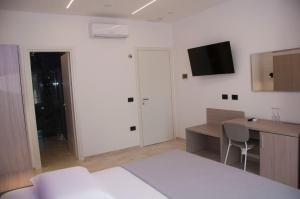 Un dormitorio con una cama y un escritorio y un televisor en la pared. en D'ANNUNZIO suites, en Martinsicuro