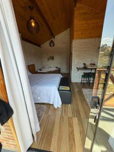 a bedroom with a bed and a table in a room at Chalé Sonho Diniz 3 in Monte Verde +56 photos