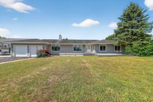 una casa con un gran césped delante de ella en Grass Lake Retreat with Game Room & Fire Pit, en Grass Lake