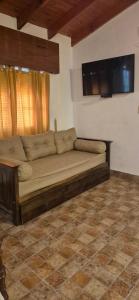 a couch in a living room with a tv on the wall at Casa Quinta La Gualeya in Gualeguay