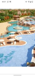 ein Swimmingpool mit Sonnenschirmen und Stühlen und Wasser in der Unterkunft قريه روزانا في الساحل الشمالي الاسكندريه كيلو 55 in Dawwār al Ḩajj Aḩmad + 2 Fotos