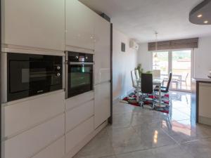 a kitchen with white cabinets and a table with chairs at Apartment Black@white in Klenovica +20 photos