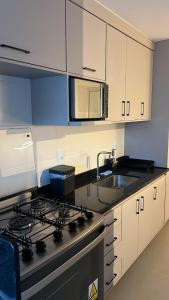 a kitchen with a stove and a sink at Conforto e estilo Praia do Forte in Cabo Frio