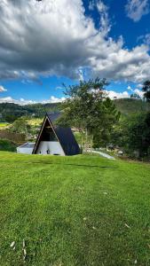 a house in a field with a grassy field at Chalé Encanto de Maria em Teresópolis in Teresópolis