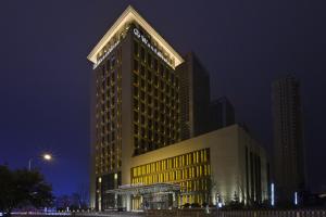 a tall building with yellow lights on it at night at Wanda Vista Shenyang in Shenyang