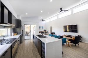 a kitchen and living room with a stove top oven at Abode On Brookwater in Mollymook