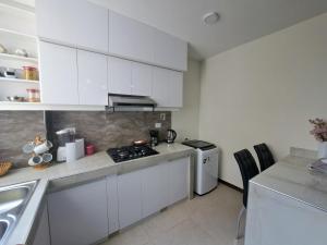 eine weiße Küche mit Herd und Spüle in der Unterkunft Cómodo departamento en barrio petrolero in Sucre