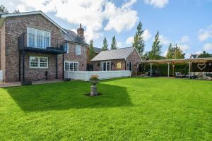 Un gran patio con una casa de ladrillo con césped verde. en Moor End Manor, en Poulton le Fylde