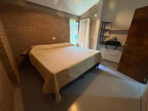 un lit dans une chambre avec un mur de briques dans l'établissement CASA EL GRINGO ubicada en Villa Parque Siquiman con vista al río tres habitaciones y capacidad para ocho personas, à Villa Parque Siquiman