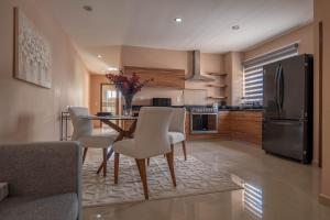 una cucina con tavolo, sedie e frigorifero di lujoso apto,en el corazón de Cancún Torre Tzalam a 5 min de la entrada a la zona hotelera a Cancún