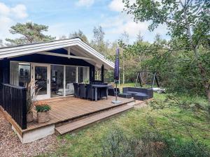 una casa con terraza con mesa y sillas en 6 person holiday home in Ålbæk, en Ålbæk