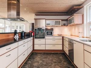 cocina grande con armarios y electrodomésticos blancos en 9 person holiday home in Skagen, en Skagen