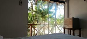 ein Schlafzimmer mit einem Fenster mit Blick auf eine Palme in der Unterkunft Palo Santo Blue Hotel in Zorritos