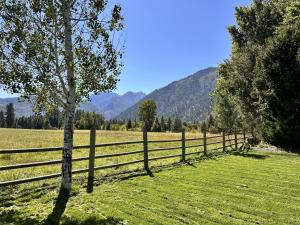 a wooden fence in a field with a tree at LeWeber Haus home in Leavenworth