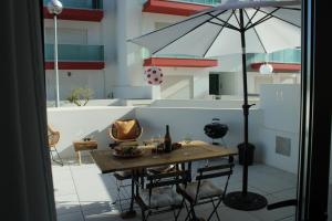 una mesa con una sombrilla en un balcón en Alto Mar Apartment 2, en Atouguia da Baleia