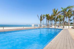 a swimming pool next to a beach with palm trees at Apartamento LUXURY Vacacional Nayarit Mexico in Tepic