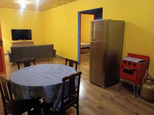 a kitchen with a table and a refrigerator in a room at Chalé Arminda Costa in Ouro Preto