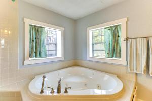 a white tub in a bathroom with two windows at Walk to Mueller Lake Park! Home with Patio and Yard in Austin +19 photos
