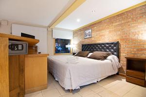 a bedroom with a large bed and a brick wall at Calafate Hostel in El Calafate