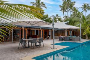 a house with a pool and a table with chairs and umbrellas at Mokusiga Villas in Tangangge