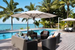 a pool with chairs and an umbrella next to the ocean at Mokusiga Villas in Tangangge