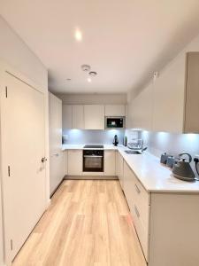 a kitchen with white cabinets and a wooden floor at Quiet Hideaway in London +11 photos
