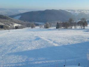 a snow covered field with a view of a lake at Camping tent with modern amenities in Trois-Ponts