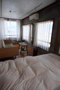Un dormitorio con una cama y una mesa y ventanas. en めくる, en Matsumoto