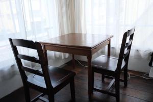 a wooden table and two chairs next to a window at めくる in Matsumoto