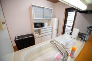 eine Küche mit einer Spüle und einer Theke mit einer Mikrowelle in der Unterkunft 飛梅の宿Tobiume inn in Dazaifu + 17 Fotos