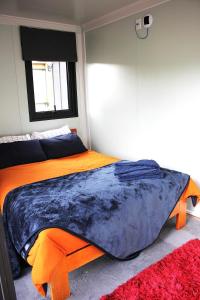 a bedroom with a bed with an orange and blue comforter at Night Sky Magic in Olive Grove in Gladstone