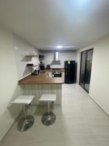 a kitchen with two white stools in a room at Comfortable apartment in Pereira