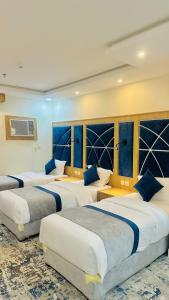 a row of four beds in a hotel room at شقق اليمامة المميز الفندقية ينبع in Yanbu