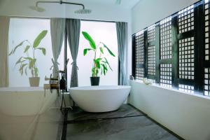a bathroom with a white tub and a window with plants at Stunning luxe 220sm villa by the sea entirely private with own pool in Busuanga