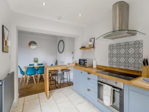a kitchen with blue cabinets and a table with chairs at Florence Cottage in Heacham
