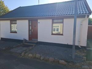 een klein wit huis met een rode deur bij 6 person holiday home in Gedser in Gedser