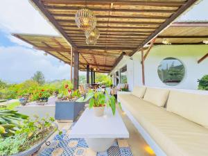 an outdoor patio with a white couch and potted plants at Un Pedacito de Santorini en el Lago Calima in Restrepo