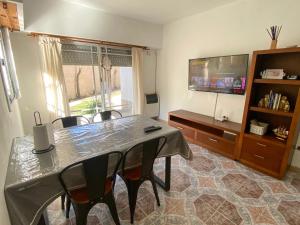 a dining room with a table and chairs and a television at Duplex 3 con cochera privada y parrilla in San Clemente del Tuyú