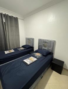 two beds in a room with blue sheets and pillows at Apartment Camilla in Martil