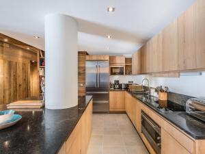 a kitchen with wooden cabinets and black counter tops at Appartement de Luxe 12 Pers. à 50m des Pistes, Spa, et Cheminée - Méribel - FR-1-565-7 in Les Allues