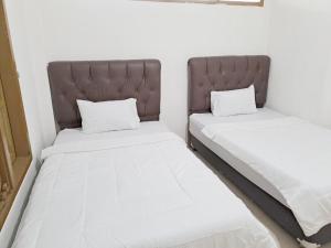 two beds sitting next to each other in a room at MAWAR Guest House By Hans Management in Bandar Lampung +16 photos