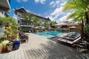 a resort with a swimming pool and lounge chairs at Howard Johnson by Wyndham Phuket Naiyang in Thalang
