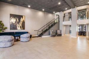 a lobby with a blue couch and chairs and a staircase at Hourglass Hotel, Trademark Collection by Wyndham in Bakersfield