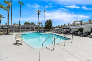 a swimming pool at a resort with chairs and palm trees at Hourglass Hotel, Trademark Collection by Wyndham in Bakersfield +81 photos
