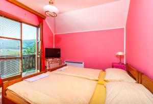 茲拉蒂博爾的住宿－維拉喬基奇旅館，配有两张床的带粉红色墙壁的客房