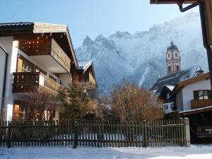 a building with a clock tower in front of a mountain at Holiday apartment Kranzberg in Mittenwald