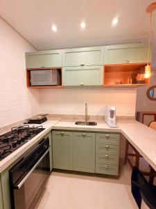 Una cocina con gabinetes verdes y un fregadero. en Pousada Pantai Maresias, en Maresias